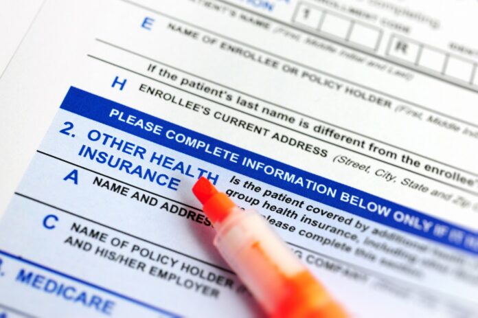 An orange felt-tip marker rests on an insurance application form.