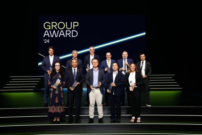 Eleven people with trophies on stage at the "Group Award '24" ceremony.